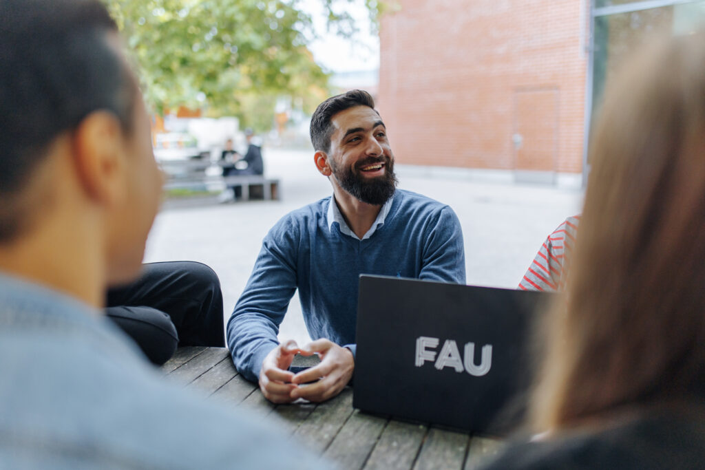 Ein Student unterhält sich mit anderen Studierenden.