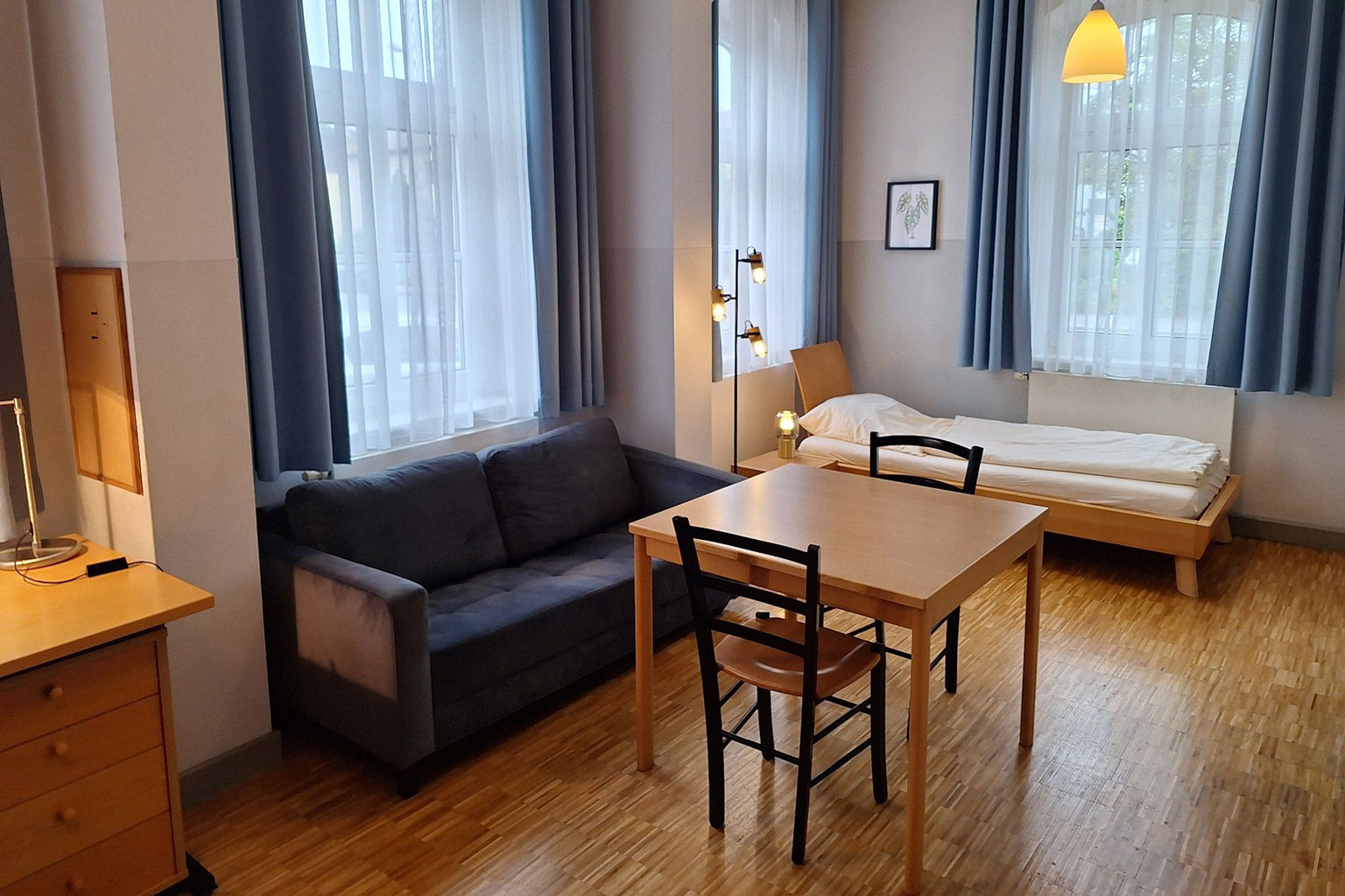 View of a room with bed, couch and dining table.