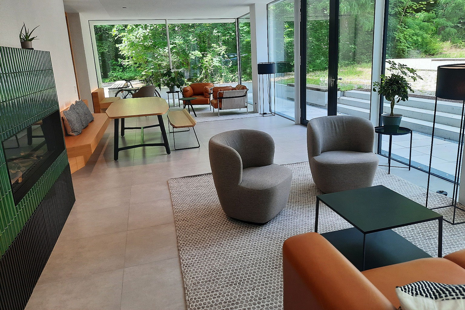 Blick in einen Aufenthaltsraum mit großem Esstisch, Sesseln und Tischen.