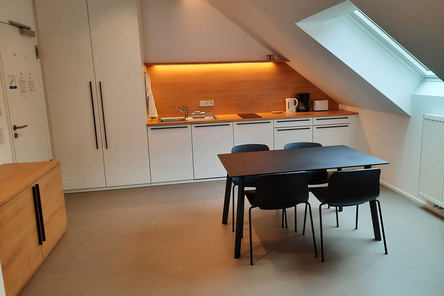 View of a dining room with kitchen units and table.