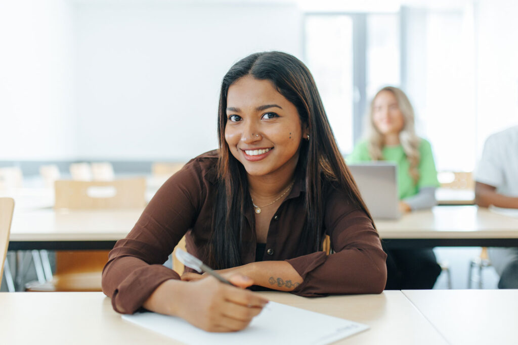 Woman sitting at a table writing on a piece of paper.