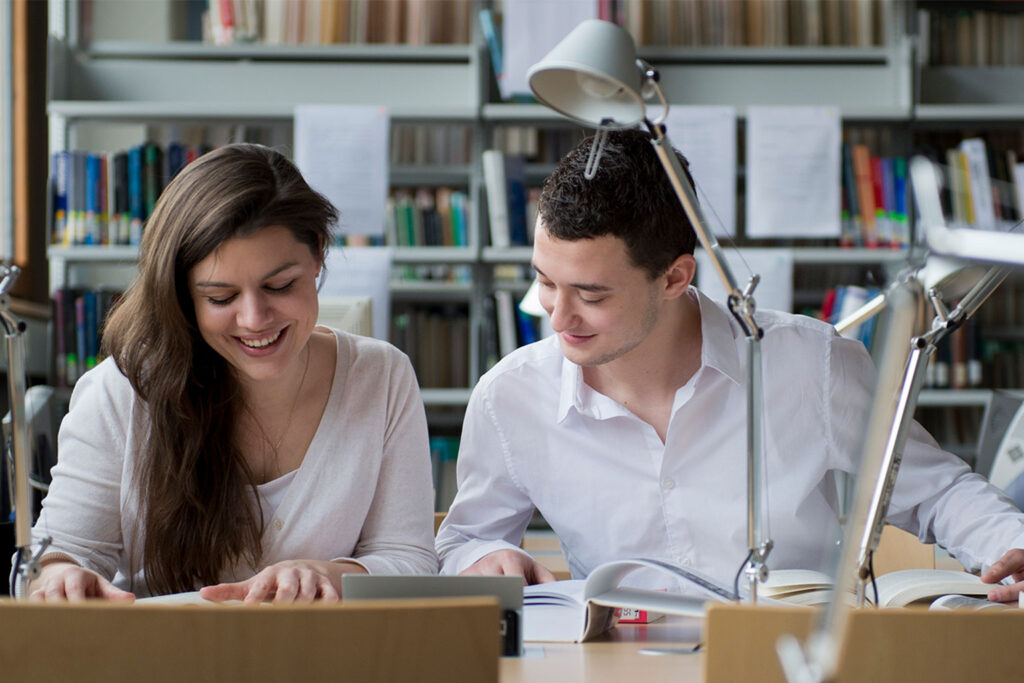 Zwei Studenten sitzen in einer Halle der Erlanger Universitätsbibliothek.