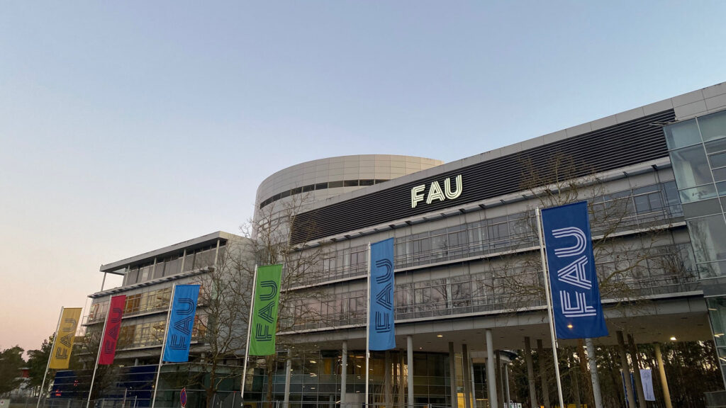 Das Verwaltungsgebäuder der FAU mit den unterschiedlichen Fakultätsfahnen vorne dran.