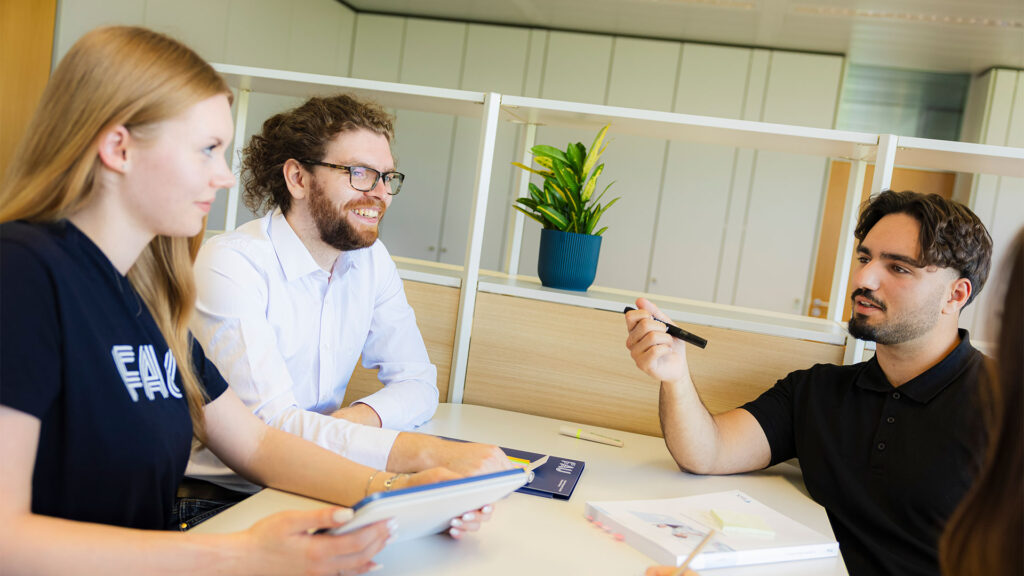 Vier Personen sitzen an einem Tisch und besprechen sich.