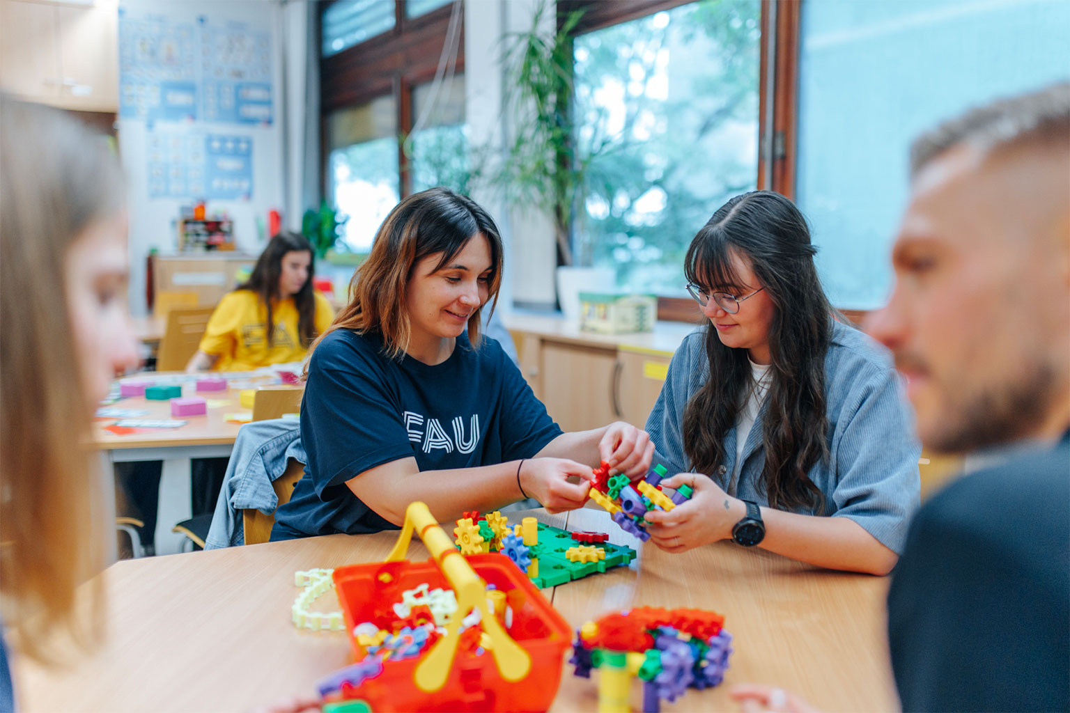 Mehrere Studentinnen und Studenten sitzen an einem Tisch und erarbeiten mit Bausteinen ein Konzept.