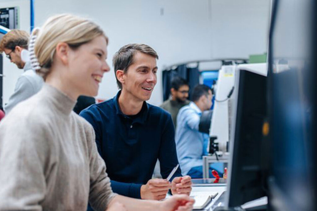 Zwei Forschende sehen gemeinsam auf einen Monitor und besprechen sich.