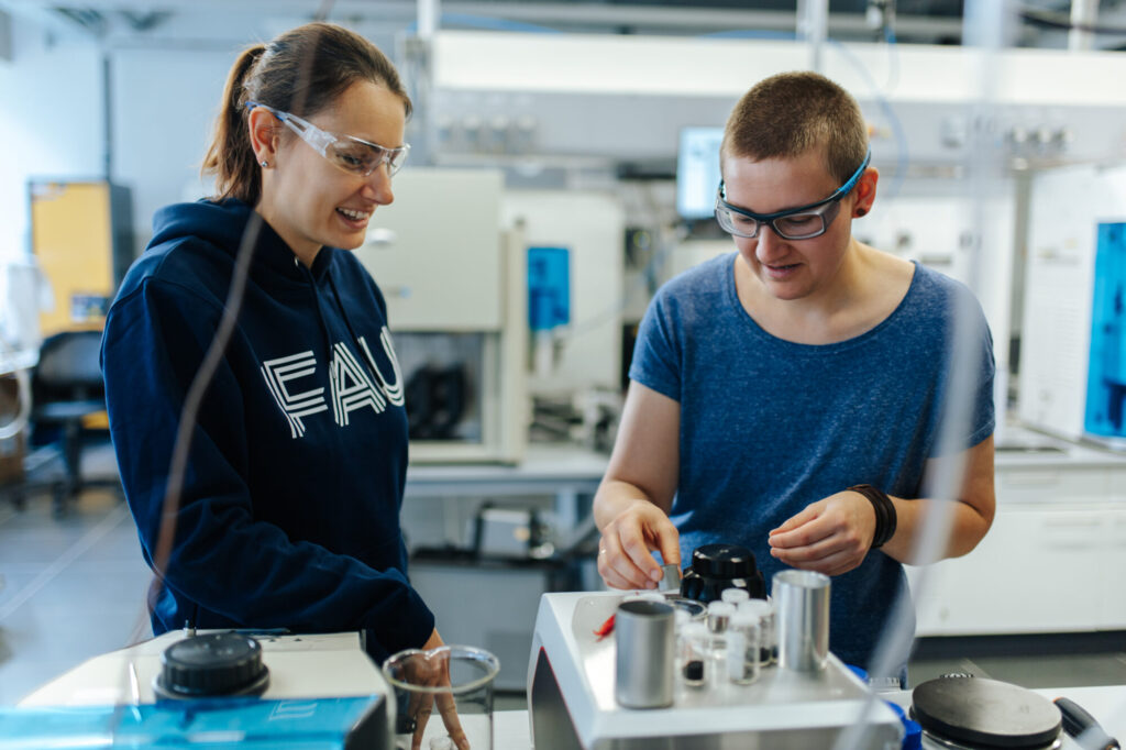 Zwei junge Frauen mit Schutzbrillen führen ein Experiment im Labor durch.