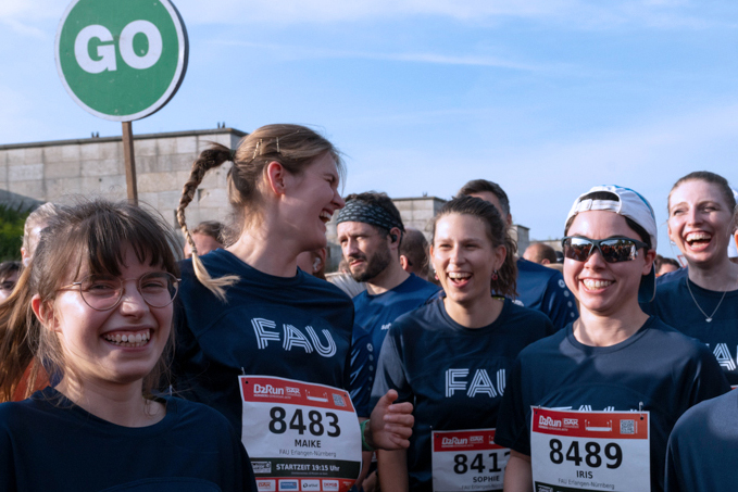 Auf dem Bild sind mehrere Teilnehmer der FAU am Firmenlauf zu sehen. Sie stehen zusammen in einer Gruppe und freuen sich gemeinsam.